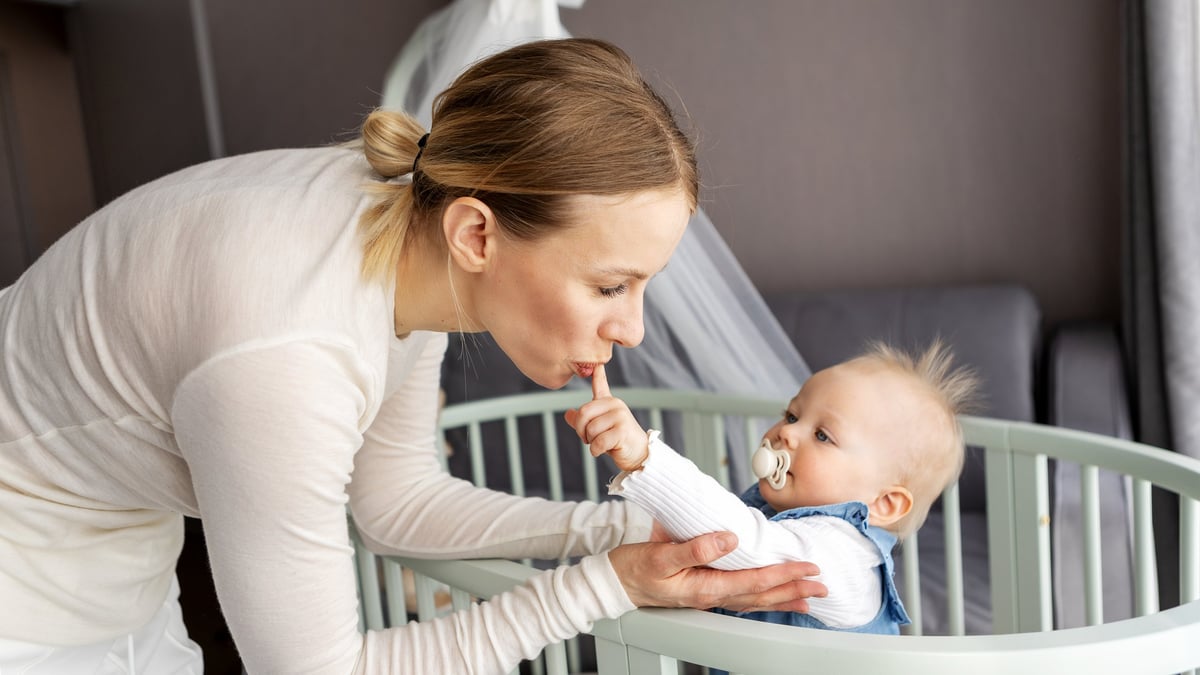 A mother kissing her baby daughter in a bright nursery