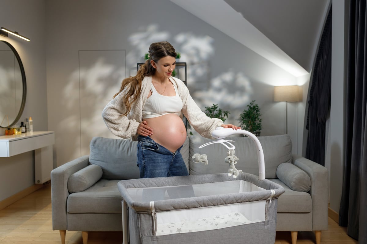 An expecting mother tidying a crib in the nursery