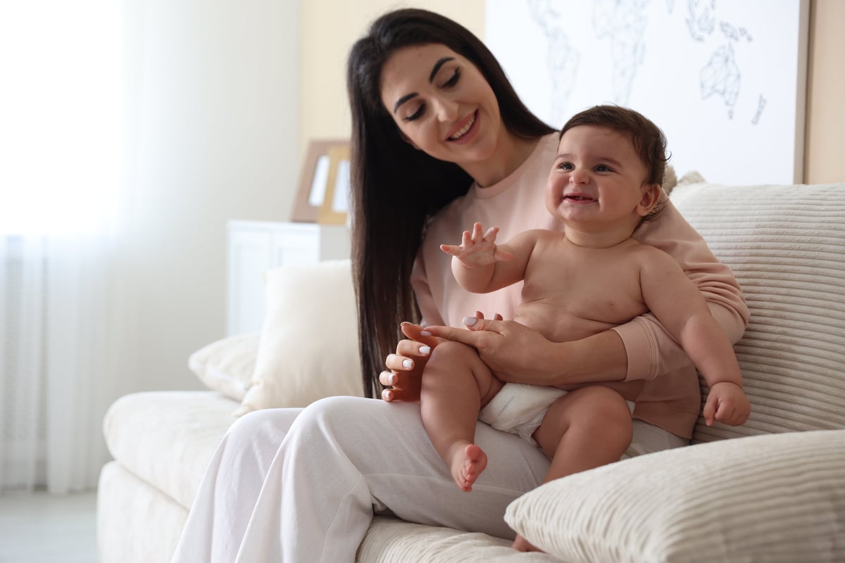 A mother smiling with her baby at home
